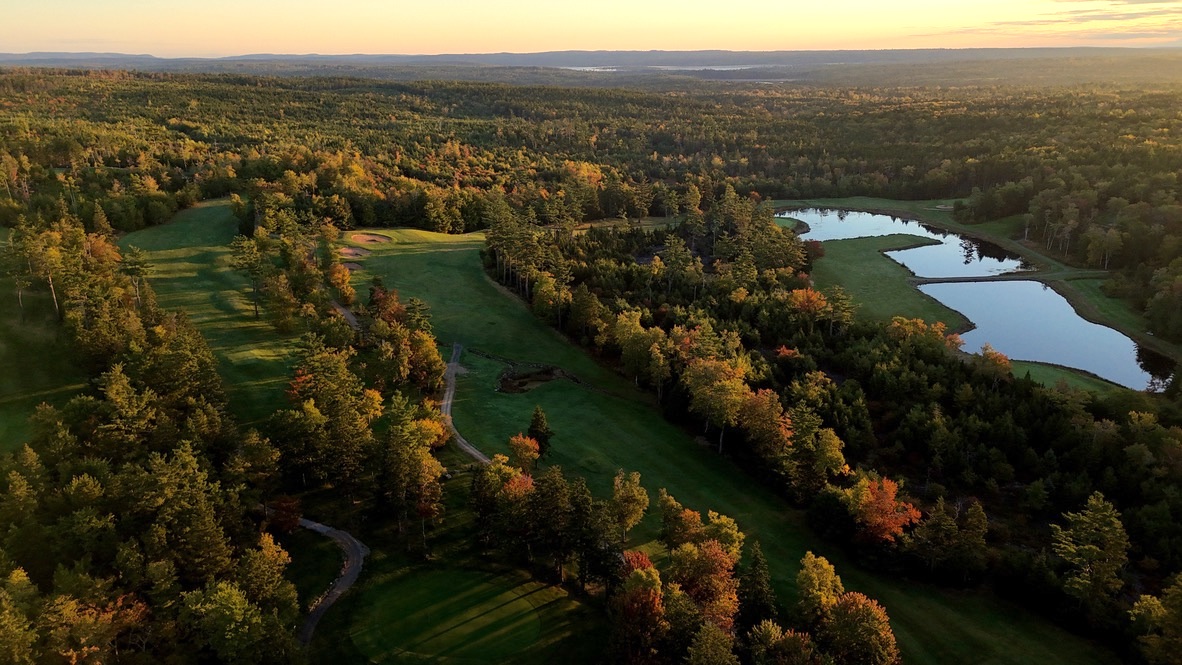 Drone fly over photo of one of the holes at the Sherwood Golf Club with autumn trees and a ponds